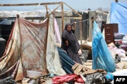 Seorang perempuan pengungsi Palestina berdiri di samping barang bawaannya ketika orang-orang menyelamatkan diri dari wilayah Mawassi di barat daya Khan Younis di selatan Jalur Gaza, 28 Juni 2024. (Foto: Bashar Taleb/AFP)