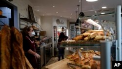 Bakers sell bread in a Boulogne Billancourt bakery, outside Paris, March 24, 2020.