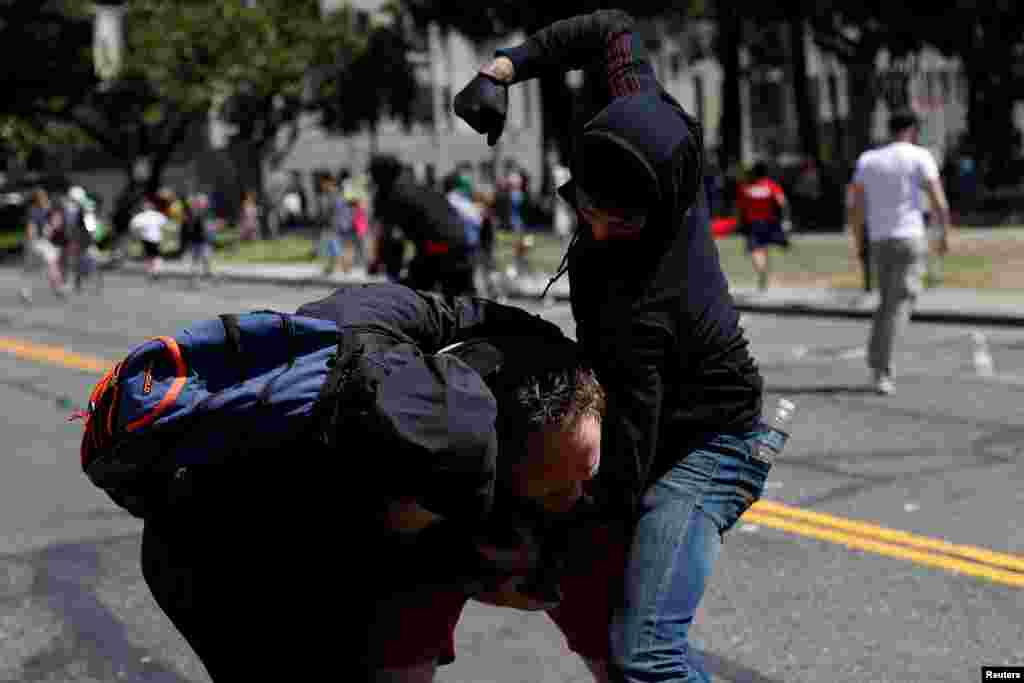 A photographer is being attacked by masked demonstrators in Martin Luther King Jr. Civic Center Park during a cancelled No Marxism in America rally and counter-protest in Berkeley, California, Aug. 27, 2017.