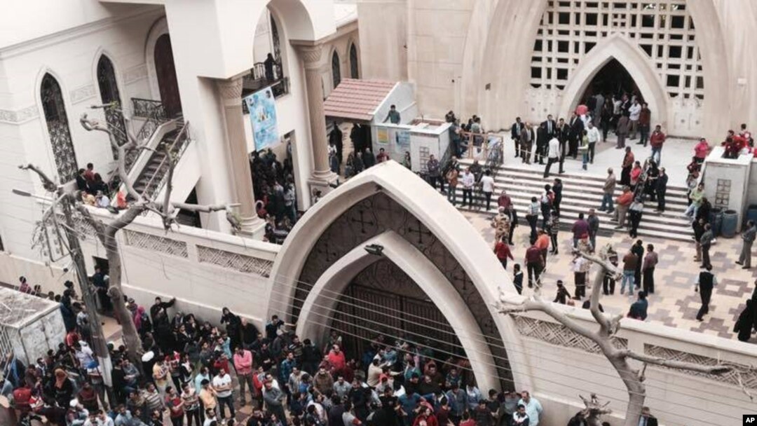 FILE - Relatives and onlookers gather outside a church after a bomb attack in the Nile Delta town of Tanta, Egypt, Sunday, April 9, 2017. 