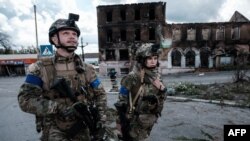 Seorang tentara Ukraina tampak melihat ke atas setelah mendengar suara drone ketika berpatroli bersama rekannya di Kota Kupiansk, wilayah Kharkiv, pada 24 September 2022. (Foto: AFP/Yasuyoshi Chiba)