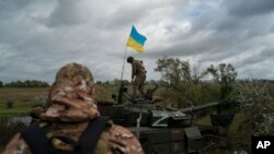 A Ukrainian national guard serviceman stands atop a destroyed Russian tank in an area near the border with Russia, in Kharkiv region, Ukraine, Sept. 19, 2022.
