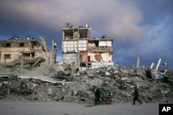 A man pushes a cart past a house that remains partly standing, but with sheets serving as makeshift walls, in an area largely destroyed by the Israeli army's air and ground offensive in Gaza City, Gaza Strip, Feb. 5, 2025.