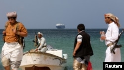 (แฟ้มภาพ) ชายติดอาวุธยืนอยู่ริมหาด ระหว่างที่เรือพาณิชย์ Galaxy Leader ถูกกล่มฮูตียึดไว้เมื่อเดือนพฤศจิกายน ทอดสมออยู่นอกชายฝั่ง อัล-ซาลิฟ เมื่อ 5 ธันวาคม 2023 (รอยเตอร์)