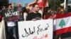 Activists hold Lebanese flags and an Arabic placard, center, that reads: "your extension is an occupation, no to the extension," during a protest against the extension of the Lebanese parliament, on a road that leads to the Parliament building, in downtow