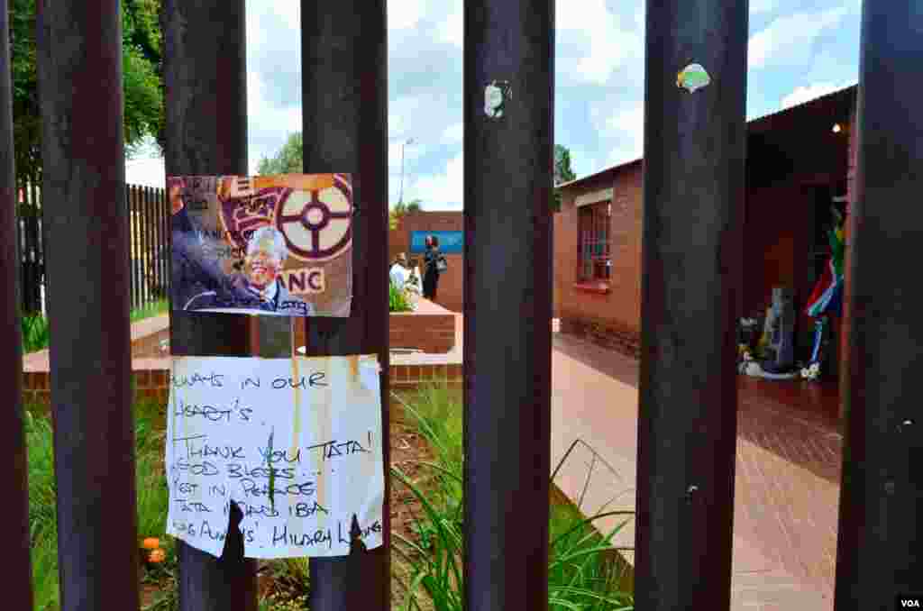 A card and note hang on the fence surrounding the Nelson Mandela National Museum, Mandela's former home, in Soweto, Dec. 12, 2013. (Peter Cox for VOA)