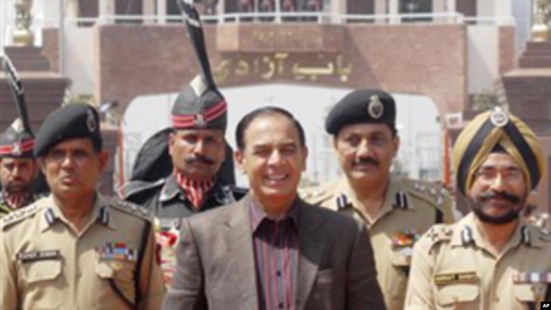 Pakistan's Interior Secretary Qamar-uz-Zaman Chaudhry walks with Indian Border Security Force officers as he arrives on the Indian side of the border at Wagah, India, March 27, 2011