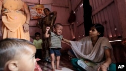 FILE - A volunteer weighs a malnourished child at the Apanalay center in Mumbai, India. 