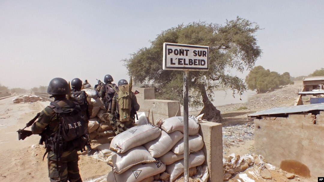 FILE - Cameroon soldiers stand guard at a lookout post as they take part in operations against the Islamic extremists group Boko Haram, their guard post is on Elbeid bridge, left rear, that separates northern Cameroon form Nigeria's Borno state, Feb. 25, 2015.