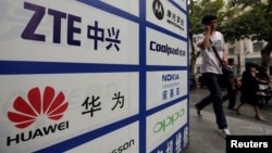 一名中國男子從武漢街頭有著華為和中興標徽的廣告牌前走過。 （資料照片）