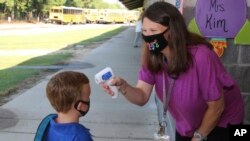 Dalam foto yang disediakan oleh Newton County Schools, asisten pengajar Crystal May berbicara dengan siswa taman kanak-kanak Lewis Henry Thompson, 5, saat dia mengukur suhu tubuhnya di Newton County di Decatur, Mississippi, 3 Agustus 2020. (Foto: AP)