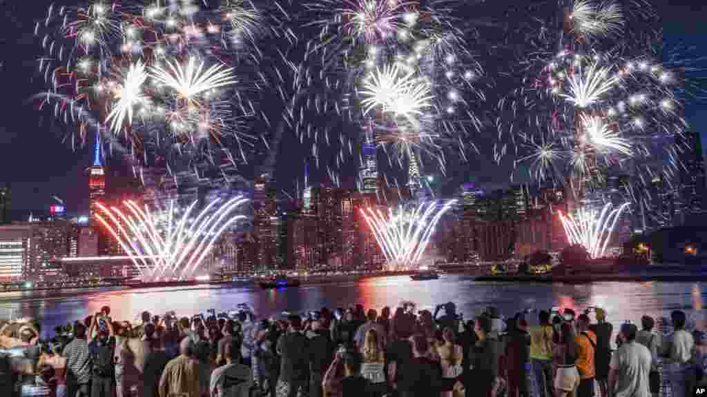Spectators gather along Williamsburg's waterfront, in the New York borough of Brooklyn, for the Macy's fireworks display as fireworks explode from barges on the East River to celebrate Independence Day, in New York, July 4, 2022.