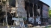 A woman stands next to a building damaged by shelling at a local market in Donetsk, Ukraine, June 19, 2022. 