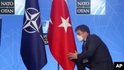 FILE - Seorang pejabat membetulkan letak bendera Turki menjelang berlangsungnya konferensi pers Presiden Turki Recep Tayyip Erdogan pada pertemuan puncak NATO di Brussels, 14 Juni 2021.