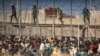 FILE - Riot police officers cordon off the area after migrants arrive on Spanish soil after crossing the fences separating the Spanish enclave of Melilla from Morocco in Melilla, Spain, June 24, 2022.