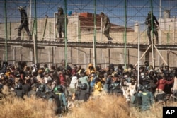 Polisi anti huru hara menutup kawasan, setelah para migran tiba di tanah Spanyol dengan melintasi pagar yang memisahkan kantong Spanyol Melilla dari Maroko di Melilla, Spanyol, Jumat, 24 Juni 2022. (AP/Javier Bernardo)