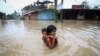 Seorang gadis menggendong adiknya saat dia mengarungi jalan yang banjir setelah hujan lebat, di pinggiran Agartala, India, 18 Juni 2022. Pada 6 September 2022, Bengaluru, India Selatan juga mengalami banjir setelah dua hari diguyur hujan deras.(Foto: REUTERS/Jayanta Dey)