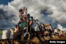 Pengungsi Rohingya yang melarikan diri dari Myanmar melintasi sawah berlumpur di Palang Khali, Bangladesh, pada Oktober 2017. (IWMF/Paula Bronstein)