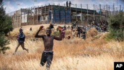 Para migran lari di tanah Spanyol setelah melintasi pagar yang memisahkan kantong Spanyol Melilla dari Maroko di Melilla, Spanyol, Jumat, 24 Juni 2022. (AP/Javier Bernardo)