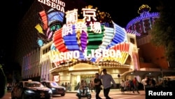 FILE - People walk in front of Casino Lisboa in Macau, China, Dec. 21, 2019. 