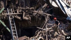 Petugas penyelamat dan petugas polisi memeriksa lokasi rumah yang hancur setelah serangan Rusia di lingkungan perumahan di pusat kota Kharkiv, Ukraina, 9 Juli 2022. (Foto: AP)