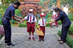 Petugas memeriksa suhu tubuh siswa pada hari pertama pembukaan kembali sekolah di Jakarta, Senin, 30 Agustus 2021. (Foto: AP)
