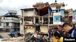 People survey a site damaged by an earthquake, in Kathmandu, Nepal, April 25, 2015. 
