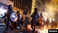 香港防暴警察走過一個燃燒的路障去驅散抗議民眾。（2019年11月2日）