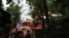 People look on a house engulfed in flames in Sittwe, Burma, June 11, 2012.