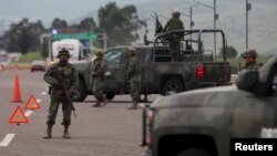 Tentara berjaga di sebuah pos pemeriksaan dekat Contepec, di negara bagian Michoacan, setelah gembong narkoba Meksiko paling terkenal, Joaquin 'El Chapo' Guzman, lolos dari penjara dengan keamanan maksimum, Sabtu (11/7).