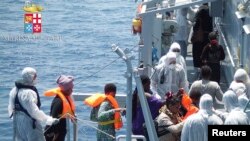 Para imigran menaiki kapal angkatan laut Italia Scirocco dalam operasi penyelamatan sekitar 40 mil dari laut Libya. 