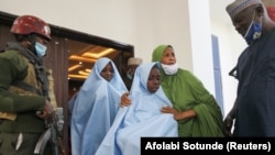 Seorang pejabat memeluk seorang gadis yang diculik dari sebuah sekolah asrama di negara bagian Zamfara, Nigeria barat laut, saat dia menuju pemeriksaan kesehatan setelah dibebaskan di Zamfara, Nigeria, 2 Maret 2021. (Foto: REUTERS/Afolabi Sotunde)