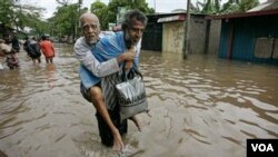 Seorang warga membantu seorang kakek untuk mengungsi dari banjir di Srilanka, Sabtu (15/1).