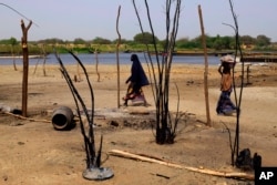 FILE - Chadian women walk past destroyed homes, in the Lake Chad shore village of N'Gouboua, March 5, 2015, following a scorched-earth attack by Boko Haram militants.
