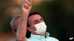 Brazil's President Jair Bolsonaro, who is infected with COVID-19, wears a protective face mask as he attends a Brazilian flag retreat ceremony outside his official residence the Alvorada Palace, in Brasilia, Brazil, Wednesday, July 22, 2020…