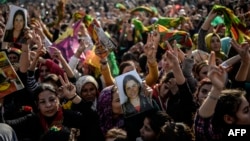 FILE - Kurds celebrating success by Kurd and peshmerga fighters to drive Islamic State militants out of Kobani hold a photo of a fighter killed in the conflict, near the Turkish-Syrian border at Suruc, in Sanliurfa province, Jan. 27, 2015.