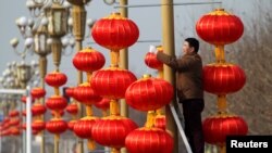 A man hangs lanterns along a street ahead of the Chinese Lunar New Year in Xuchang, Henan province, China, January 15, 2017. 