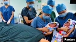Para perawat menunjukkan sepasang bayi kembar di Xi'an, Provinsi Shaanxi, 16 Agustus 2012. (Foto: Reuters)