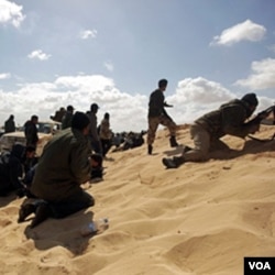 Para pemberontak Libya mencari perlindungan dalam bentrokan dengan pasukan pro-Gaddafi di kota Ajdabiya (21/3).