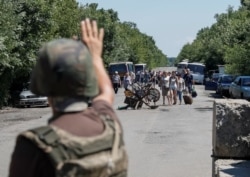 A member of the Ukrainian State Border Guard Service gives a sign to people to stop as they approach a checkpoint at the contact line between pro-Russian rebels and Ukrainian troops in Mayorsk, Ukraine July 3, 2019.