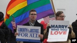 Spencer Geiger dari Virginia Beach (kiri) dan Carl Johanson dari Norfolk membawa kertas bertuliskan pesan dalam aksi demo di luar Pengadilan Norfolk, Virginia, 14 Februari 2014.