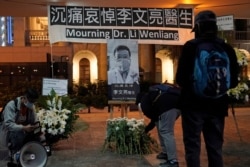 FILE - People attend a vigil for Chinese doctor Li Wenliang, in Hong Kong, Feb. 7, 2020. Li, who got in trouble with authorities for sounding an early warning about the coronavirus outbreak, died Feb. 7, 2020, after being infected.