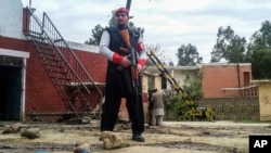 FILE - A Pakistani security officer stands alert at the site of a Taliban suicide bombing in Pakistan's tribal region of Mohmand, Feb. 15, 2017. 