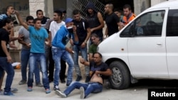Palestinians try to evacuate a wounded man during clashes with Israeli troops at Qalandia checkpoint near occupied West Bank city of Ramallah October 6, 2015.