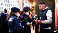 Polisi memeriksa status vaksinasi seorang pria di sebuah pasar di Wina, Austria (19/11). Uni Eropa menangguhkan perjalanan dari bagian selatan Afrika setelah mendeteksi varian baru COVID-19.