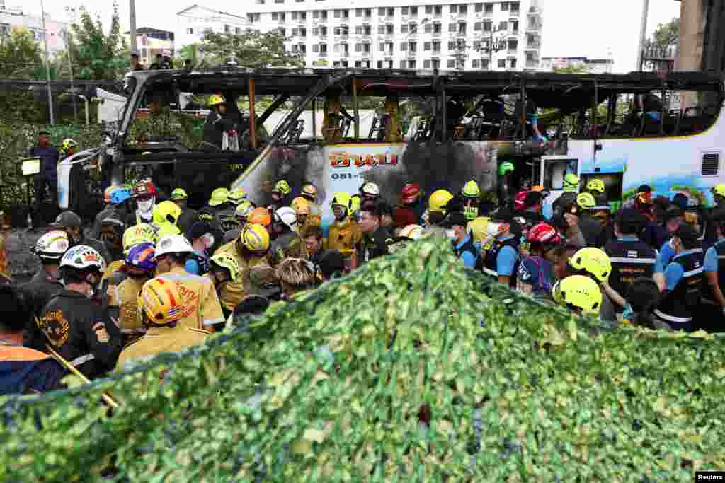 A green cover is set up as firefighters remove bodies from a burnt-out bus that was carrying teachers and students from Wat Khao Phraya school, on the outskirts of Bangkok, Thailand. At least 23 people died when a school bus carrying more than 40 students and teachers on a field trip caught fire in the outskirts of the capital, police said.