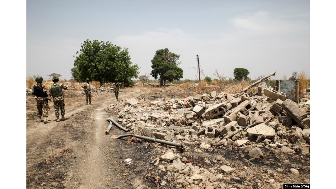 Soldiers walk among the ruins of the Government Secondary School in Chibok, Nigeria, March 25, 2016.