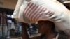 A displaced refugee woman carries a rice bag after receiving it as humanitarian aid at the airport outside the capital Bangui, Jan. 7, 2014.