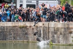 FILE - The statue of 17th century slave trader Edward Colston falls into the water after protesters pulled it down during a protest against racial inequality, in Bristol, Britain, June 7, 2020.