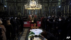 Seorang wanita mencium layar pelindung di atas peti mati Patriark Irinej saat dia berbaring di gereja Kongregasional di Beograd, Serbia, Sabtu, 21 November 2020. (Foto: AP)